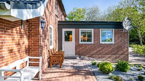 A brick building with a white door, a small window, and a satellite dish. - Apartment 'Friesenstube' with Shared Terrace, Shared Garden and Wi-Fi (Emmelsbüll-Horsbüll)