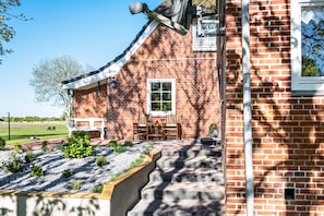 A brick house with a porch, a window, and a satellite dish.