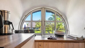 A kitchen with a large arched window, a coffee maker, and a toaster on the counter. - Apartment 'Friesenstube' with Shared Terrace, Shared Garden and Wi-Fi (Emmelsbüll-Horsbüll)