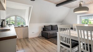 A modern kitchen with a wooden countertop and a built-in oven, a dining area with a white table and chairs, and a cozy seating area with a sofa and cushions. - Apartment 'Friesenstube' with Shared Terrace, Shared Garden and Wi-Fi (Emmelsbüll-Horsbüll)