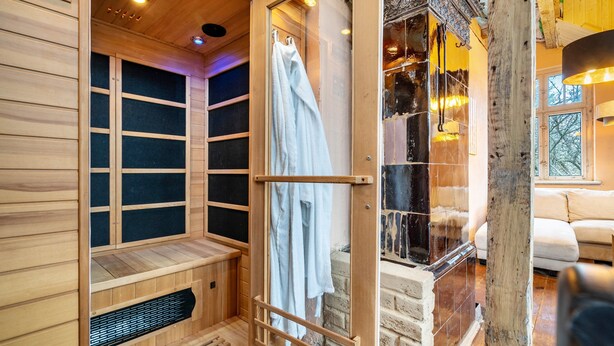 A sauna with wooden walls and a glass door, a bench, and a towel rack. - Holiday Home 'Seeblick' with Lake View, Private Terrace and Wi-Fi (Rheinsberg)