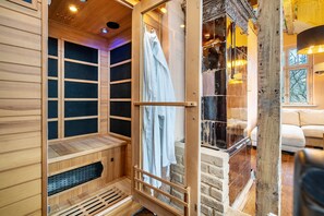 Uma sauna com paredes de madeira, porta de vidro, um banco e um porta-toalhas.