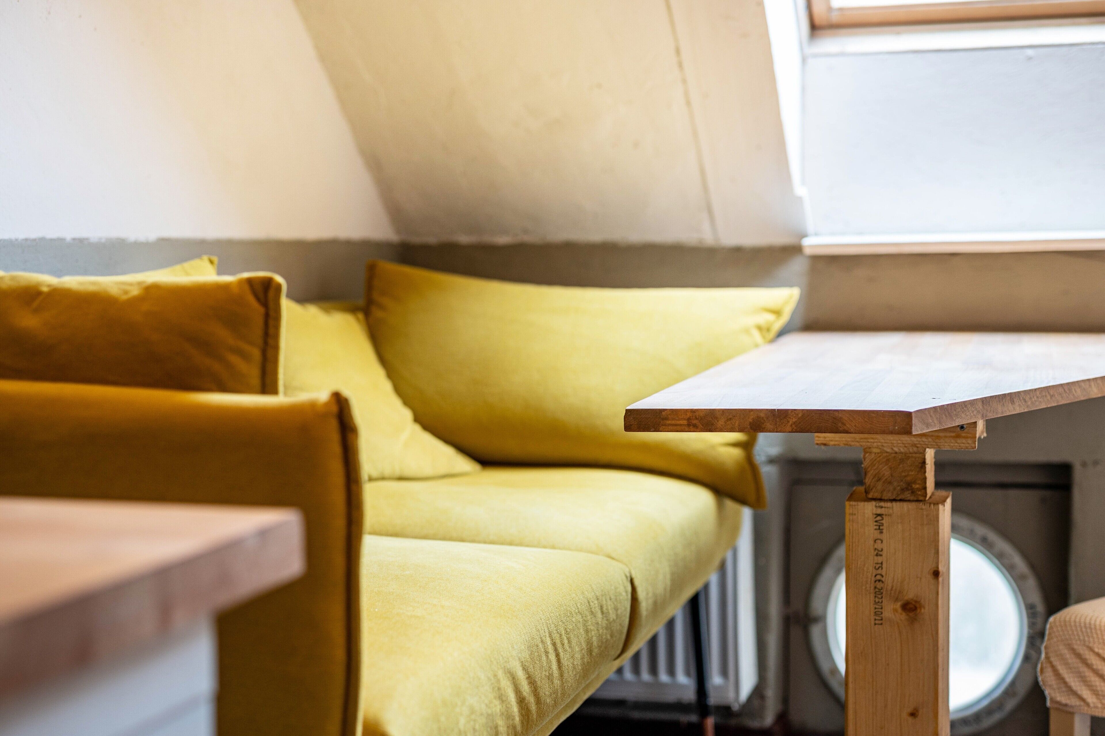 A yellow sofa in a room with a wooden table and a radiator.