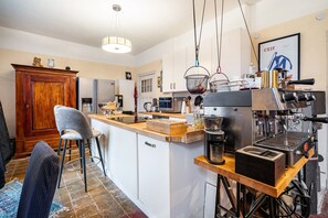 A modern kitchen with a central island, a coffee machine, and hanging baskets. - Holiday Home 'Seeblick' with Lake View, Private Terrace and Wi-Fi (Rheinsberg)