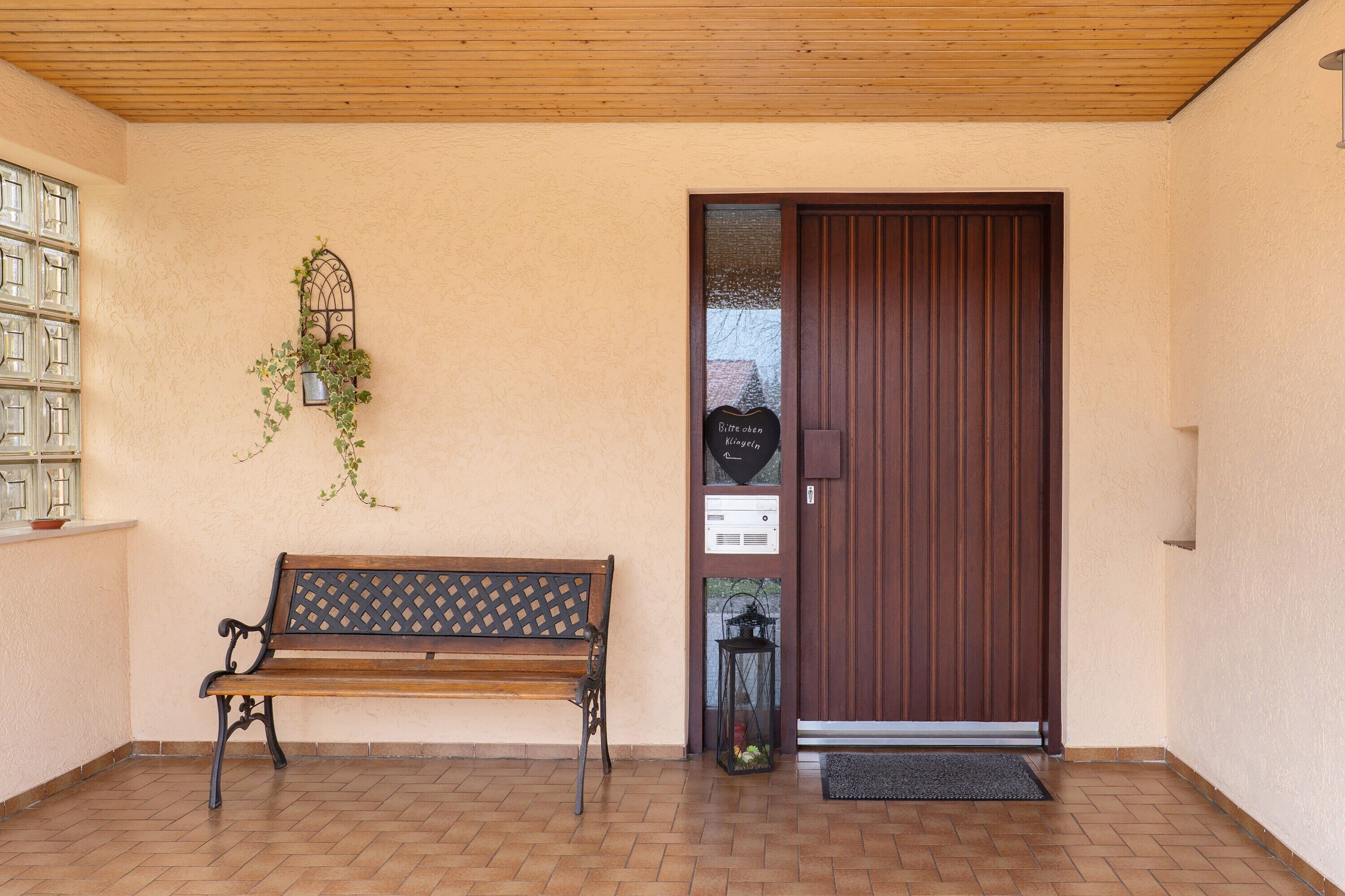 A wooden bench, a door, a wall-mounted planter, and a small table with a plant.