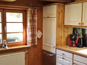 A kitchen with wooden cabinets, a window with a plaid curtain, and a coffee maker on the counter. - Apartment 'Ferienwohnung, 60 Qm' with Private Terrace, Shared Garden and Wi-Fi (Breitnau)
