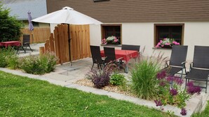 Un patio con mobiliario exterior, valla de madera y jardineras en el edificio.