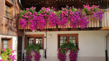 Un bâtiment doté d’un toit en tuiles, de balcons en bois et de jardinières ornées de fleurs roses.