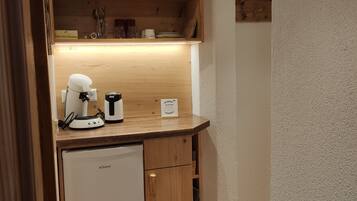 A compact kitchenette with a built-in refrigerator, a coffee maker, and a microwave.
