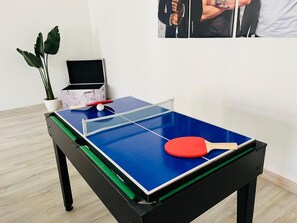 Et bordtennisbord med en rød ketcher, en potteplante og et kort på bordet.