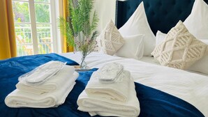 Ein ordentlich bezogenes Bett mit weißen Laken, einer blauen Tagesdecke und dekorativen Kissen.