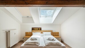 Ein Schlafzimmer mit Dachfenster, einem Holzbettgestell, einem Nachttisch und einer Heizung.