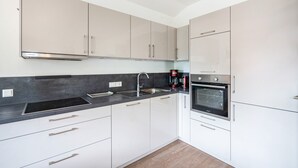 Eine moderne Küche mit weißen Schränken, einer schwarzen Arbeitsplatte, Edelstahlgeräten und einem eingebauten Backofen.