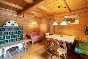 L’intérieur d’un chalet en bois, avec un banc, une table, un canapé et un tableau accroché au mur.