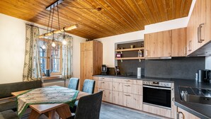 Une cuisine moderne avec des meubles en bois, une table à manger avec des chaises et un four encastré.