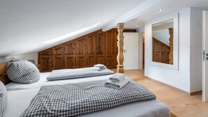 Une chambre avec deux lits, un lambris en bois, un grand miroir et une lucarne.