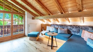 Une pièce avec un plafond en bois, de grandes fenêtres, un canapé, une table et une vue sur la verdure à l’extérieur.