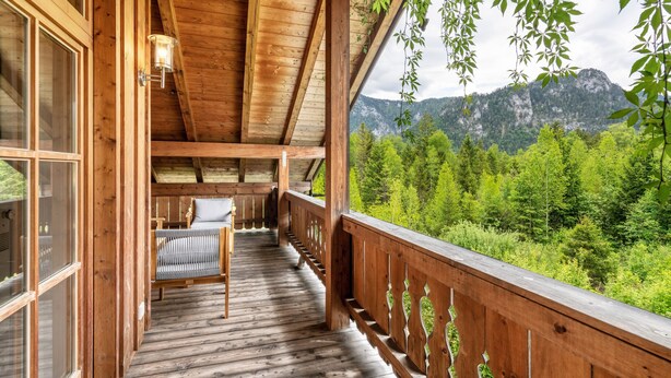 Une terrasse en bois offrant une vue sur une forêt et des montagnes.