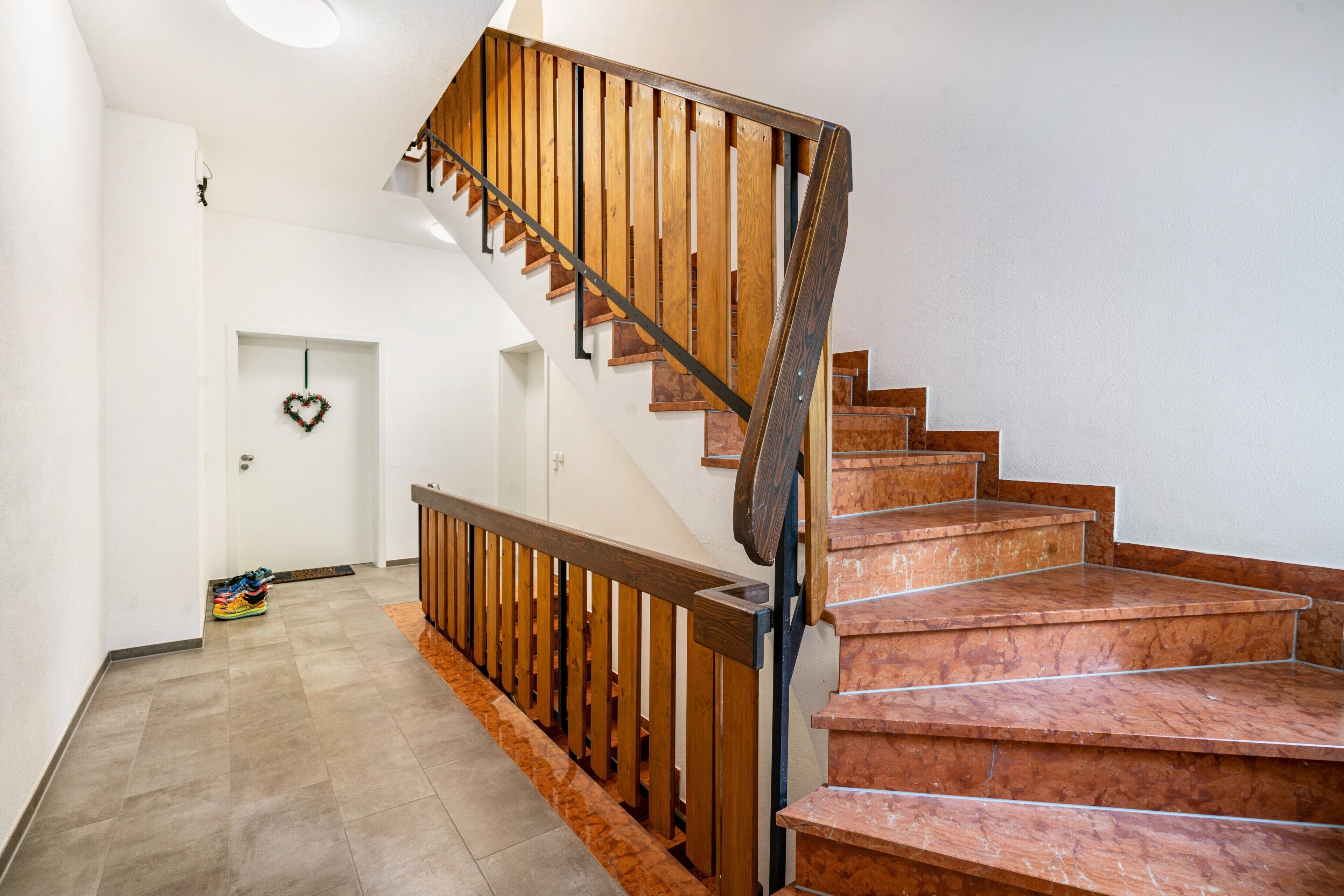 Un escalier avec des rampes en bois et des marches en marbre, menant à l’étage supérieur.