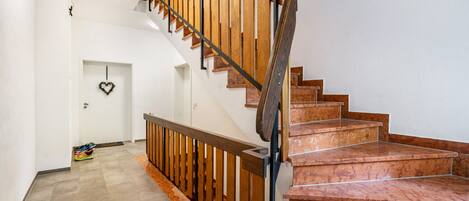 Un escalier avec des rampes en bois et des marches en marbre, menant à l’étage supérieur.