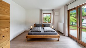 A modern bedroom with a wooden bed, bedside lamps, a window with a view, and a ceiling light fixture. - Apartment 'Haus Katharina 2' with Mountain View, Private Terrace and Wi-Fi (Inzell)