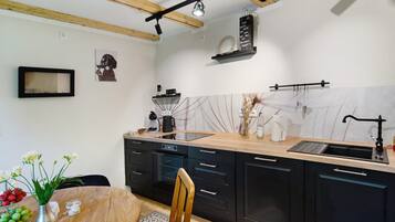 A modern kitchen with wooden beams, a central island, black cabinets, and a white backsplash.