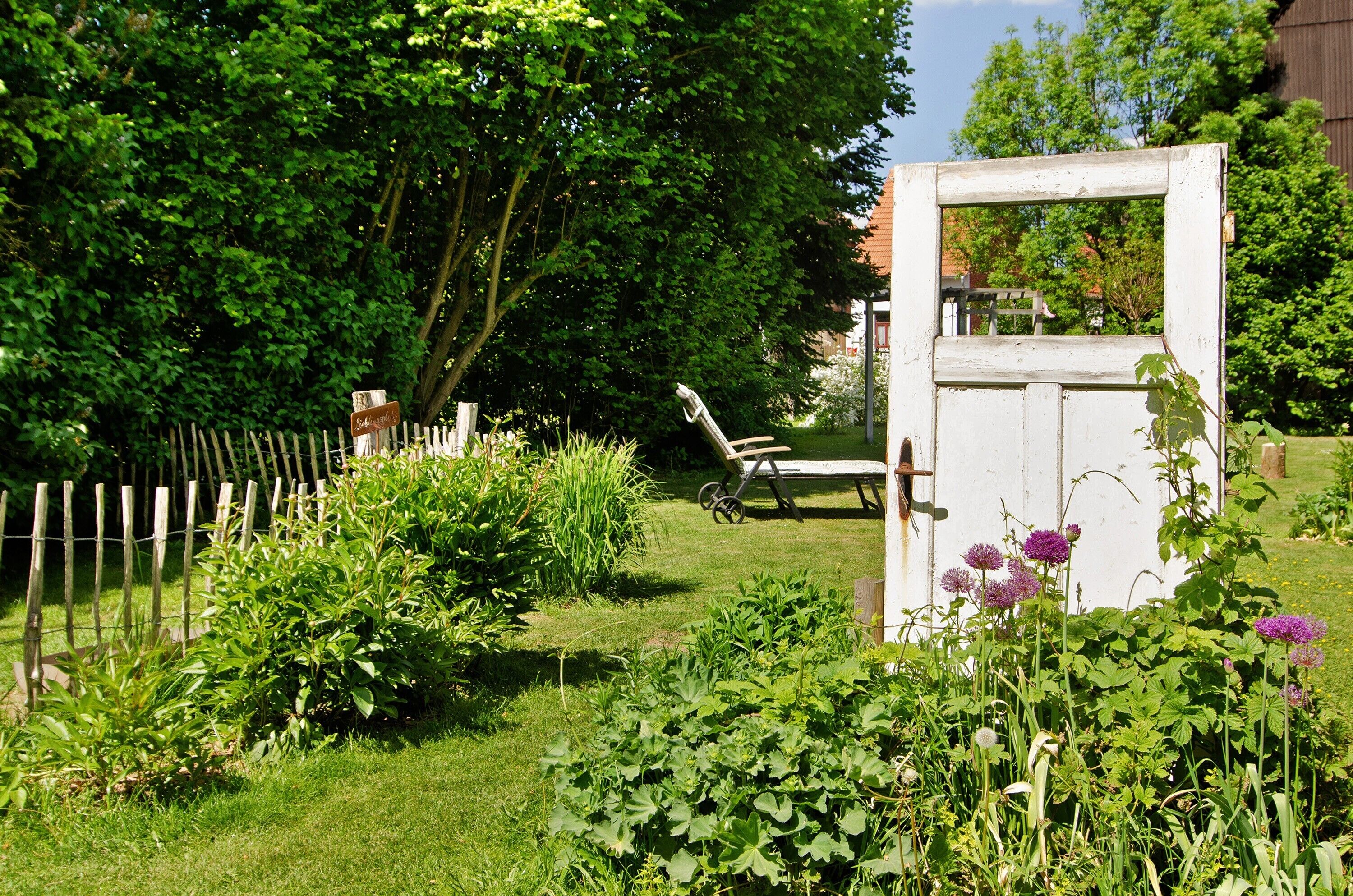 Ein Garten mit Holzzaun, einer Bank und einer weißen Tür.