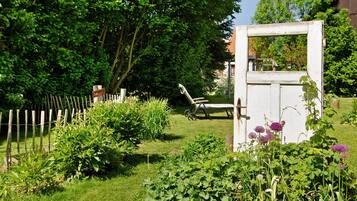 Ein Garten mit Holzzaun, einer Bank und einer weißen Tür.