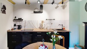 Een moderne keuken met een houten aanrecht, zwarte kastjes en een eethoek met een tafel en stoelen.