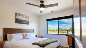 A bedroom with a bed, a ceiling fan, a window with a view, and a nightstand. - Dark Sky Retreat Near Sedona • Hot Tub, Sauna & Mountain Views (Cornville)