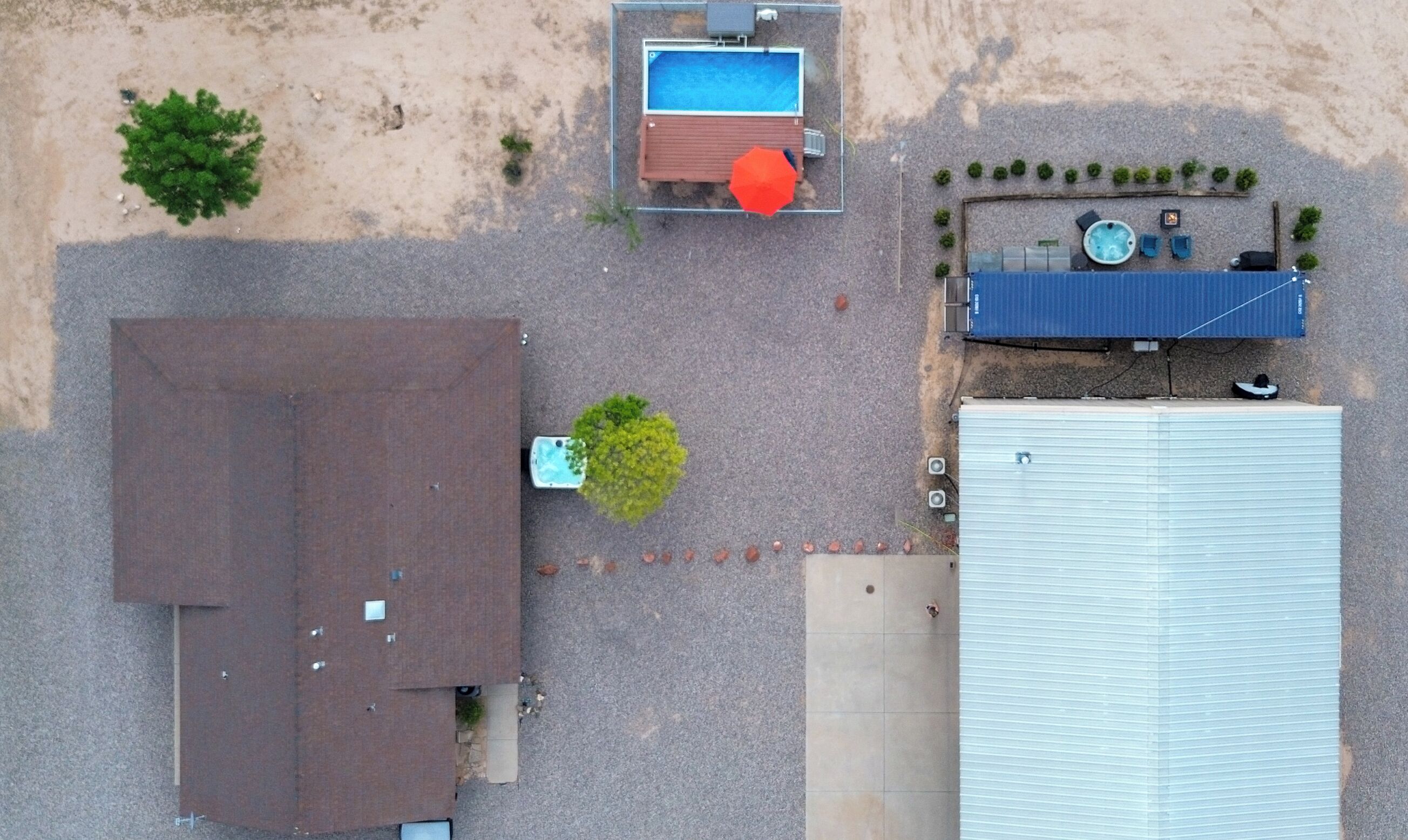 An aerial view of a property with a swimming pool, a hot tub, and a covered outdoor area.