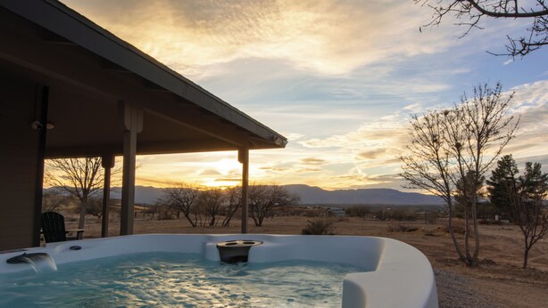 A hot tub with a view of mountains and a sunset. - Dark Sky Retreat Near Sedona • Hot Tub, Sauna & Mountain Views (Cornville)