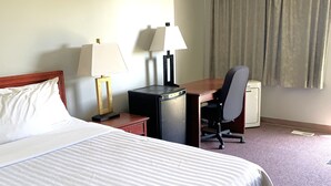 A hotel room with a large bed, two bedside lamps, a desk with a chair, and a window with curtains. - Value Stay Clean Room at Castle Motel (Edson)