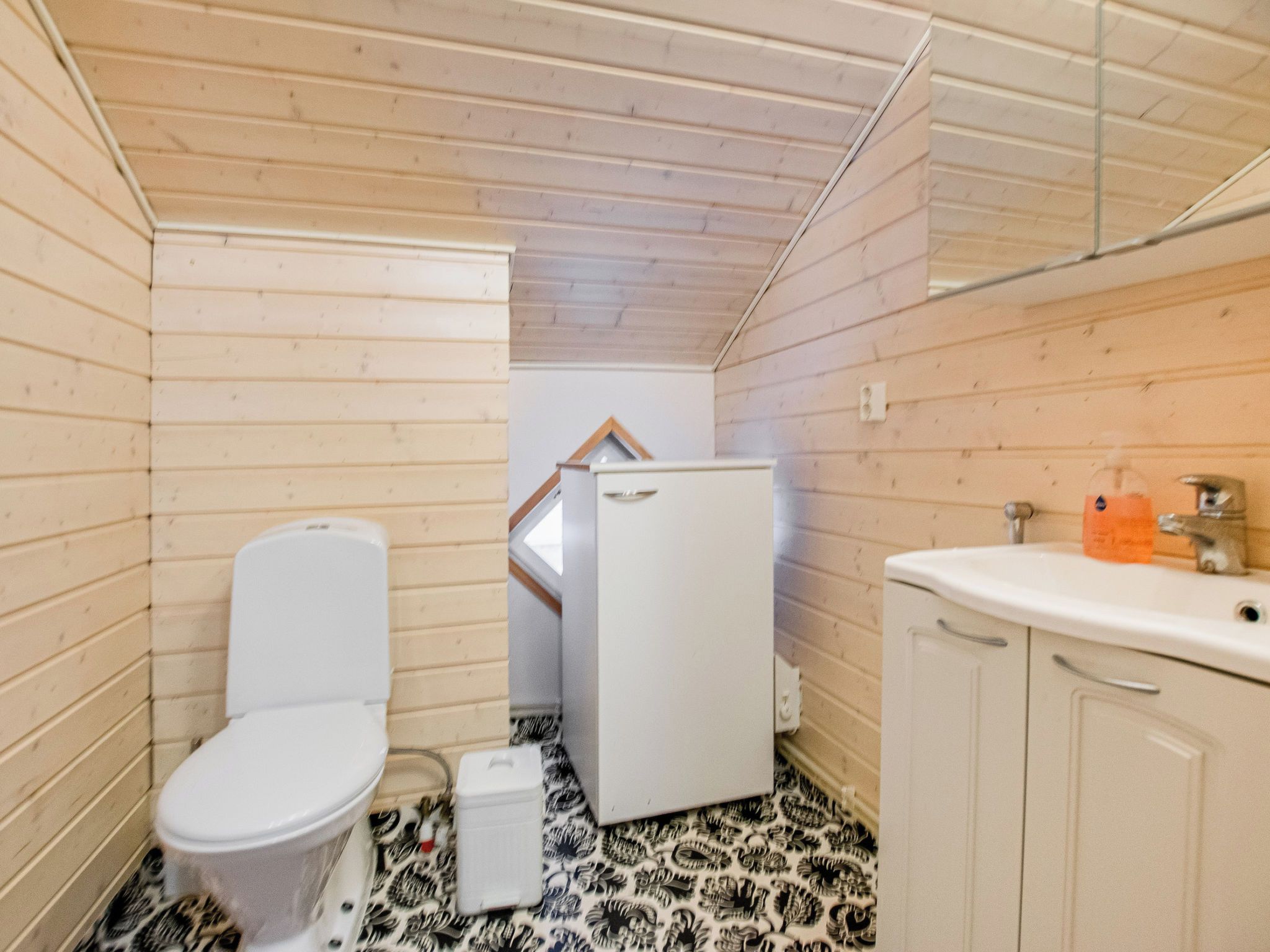 Pieni, käytännöllinen kylpyhuone, jossa on valkoinen wc-istuin, valkoinen pesuallas ja valkoinen kaappi.