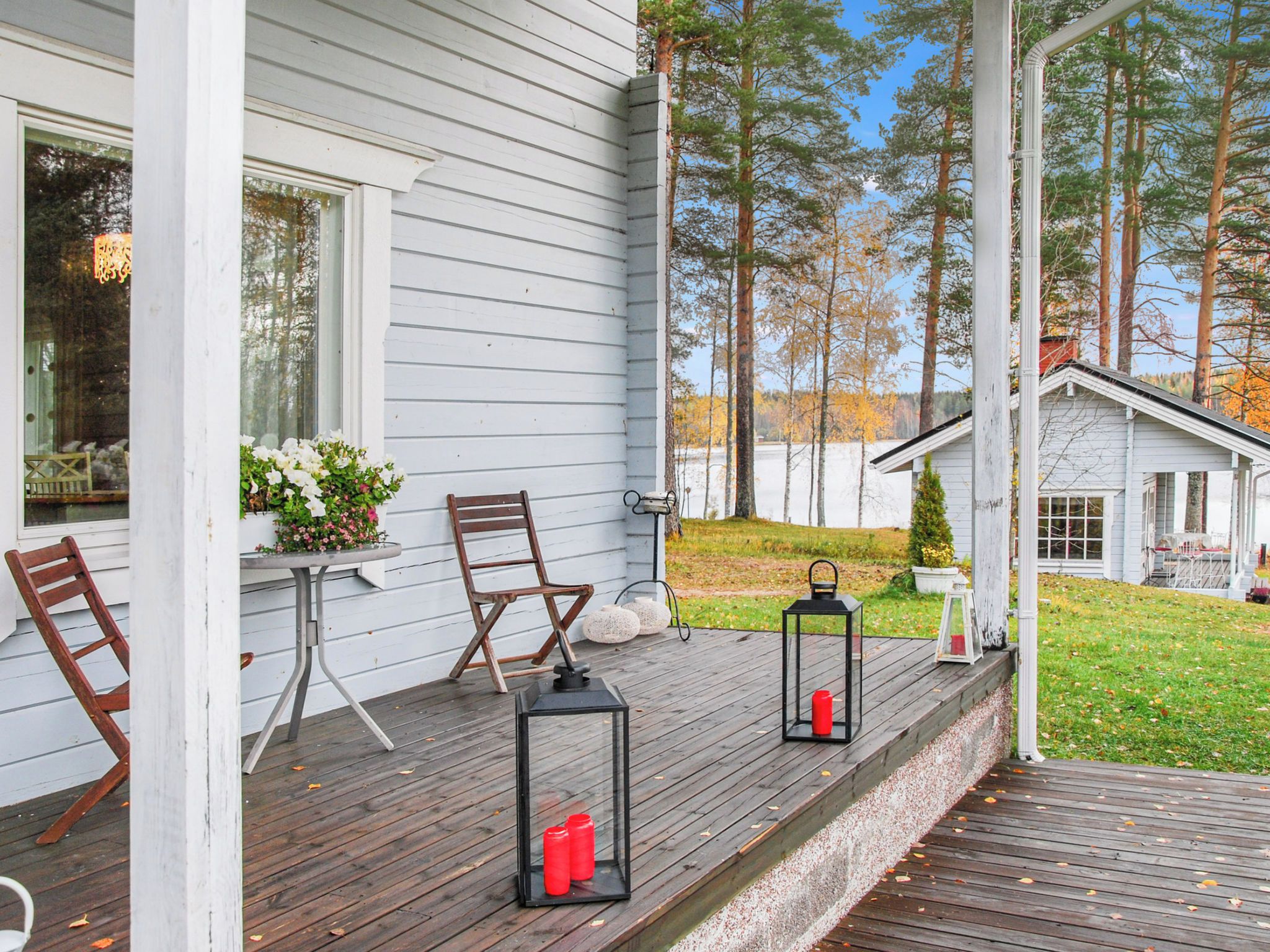 A wooden deck with outdoor seating, a small table with flowers, and two lanterns.