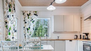 Una cucina moderna con mobili bianchi, un piano di lavoro in legno e un'area pranzo con sedie e tavolo bianchi.