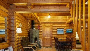 Interior de cabana de madeira com lareira, área de estar e televisão.