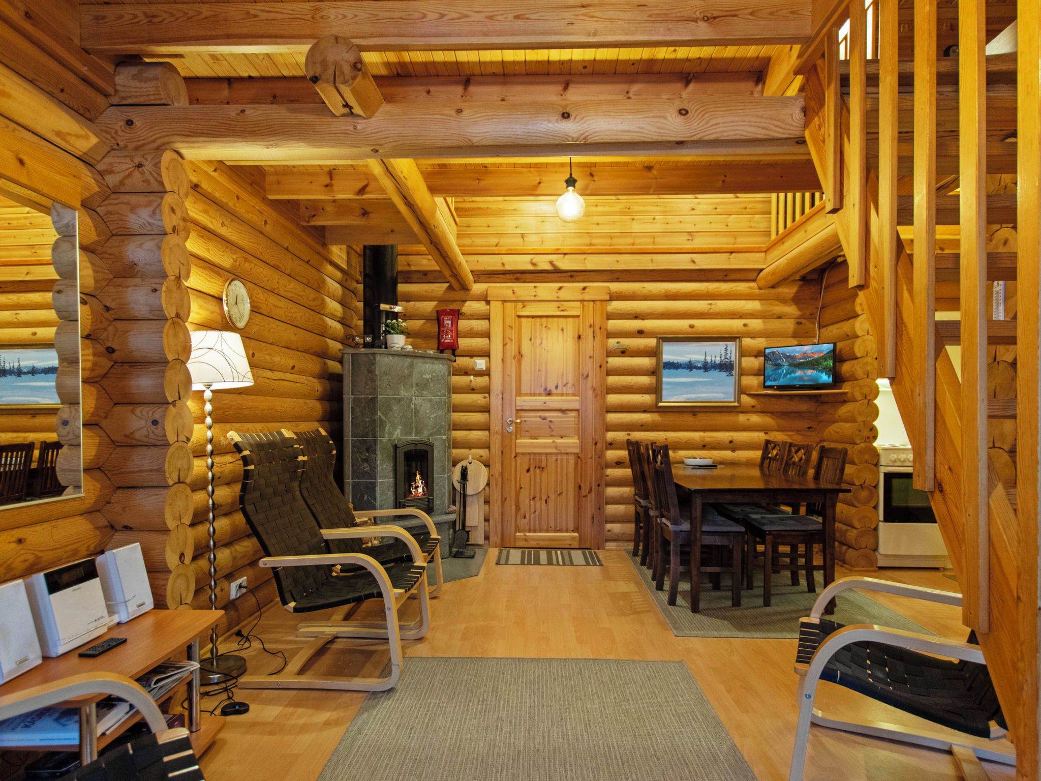 A log cabin interior with a fireplace, wooden furniture, and a television.