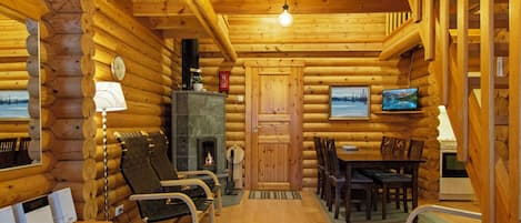 A log cabin interior with a fireplace, wooden furniture, and a television.