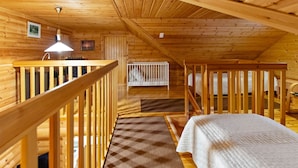 Uma cabana com interior de madeira, uma escada e uma cama.