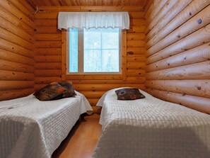 Une cabine équipée de deux lits simples, chacun avec un oreiller et une couverture blanche.