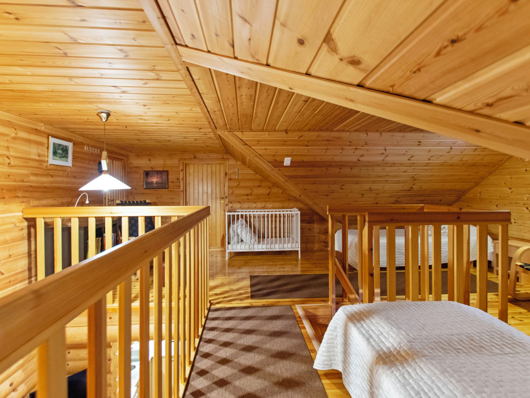 Interno di una baita in legno con camera a soppalco, angolo cottura e ringhiera in legno.
