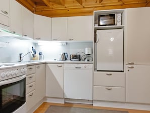 A compact kitchen with a built-in oven, microwave, and dishwasher. - Kilpolan orvokki by Interhome (Jämijärvi)