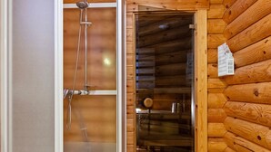 Uma cabana de madeira com porta de vidro que dá para uma área de chuveiro.