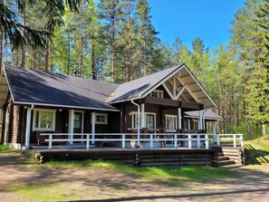 A log cabin with a porch, multiple windows, and a clear view of the surrounding forest. - Kilpolan pauliina by Interhome (Jämijärvi)