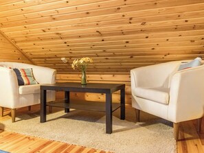 A cozy room with a wooden ceiling, a small table with a vase of flowers, two white armchairs, and a beige carpet. - Kilpolan pauliina by Interhome (Jämijärvi)