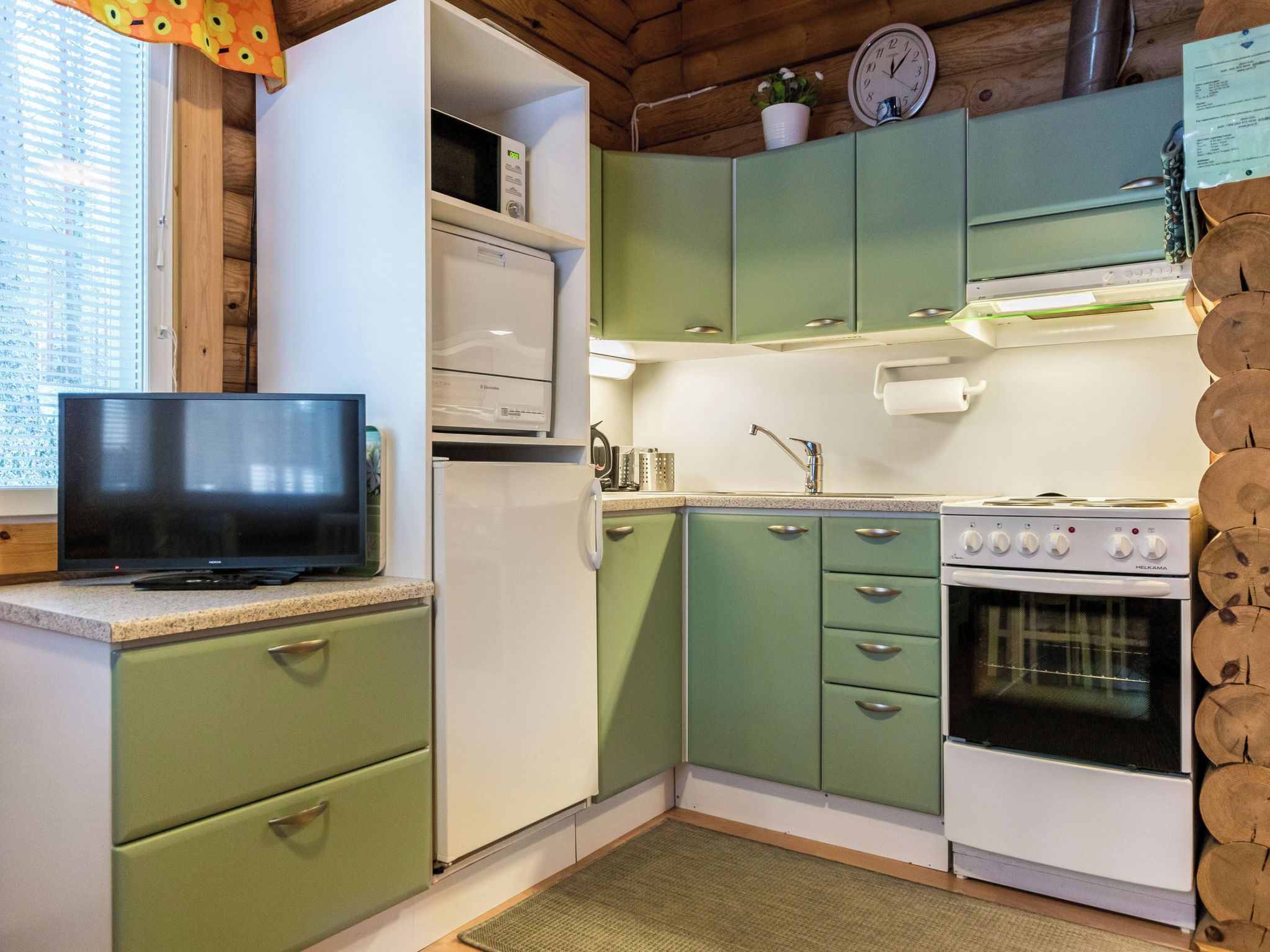 A compact kitchen with a microwave, stove, and green cabinets.
