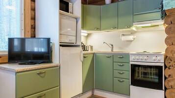 A compact kitchen with a microwave, stove, and green cabinets.