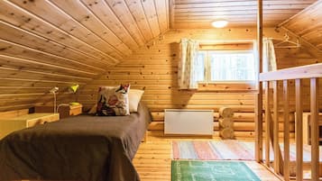 Et hyggeligt træhytteværelse med seng, skrivebord, radiator og et vindue med gardiner.