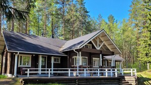 Eine Blockhütte mit Veranda, mehreren Fenstern und freiem Blick auf den umliegenden Wald.